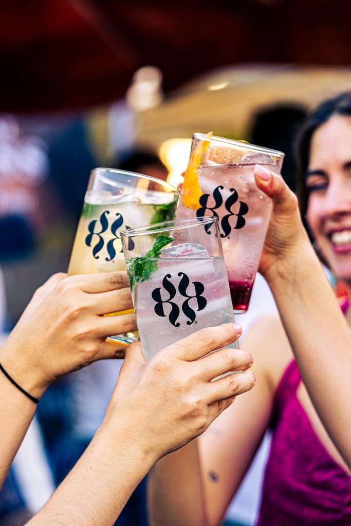 Friends clinking glasses celebrating in a lively outdoor setting.